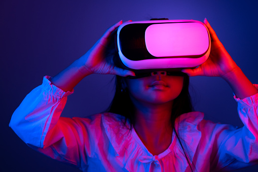 Asian child girl wearing VR glasses Playing games or watching videos in the dark with blue and red lights