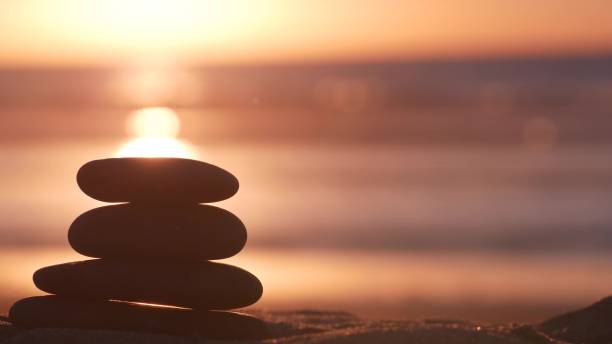 istock Stack of pebble stones, sandy ocean beach, sunset sky. Rock balancing by water. 1371916638