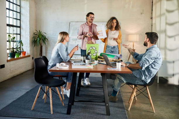 Happy team of environmentalists having a meeting at casual office. Group of happy freelancers talking about recycling problems during a meeting at casual office. recycling bin photos stock pictures, royalty-free photos & images