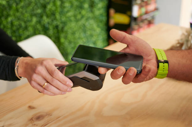 istock close up hands detail using a cell phone and a wireless dataphone to contactless pay in a store 1371919021