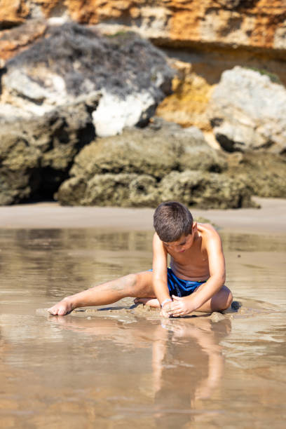 istock Little kid sitting on a rocky beach 1371919050