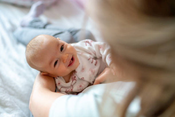 mujer cargando a su bebé en casa - newborn fotografías e imágenes de stock