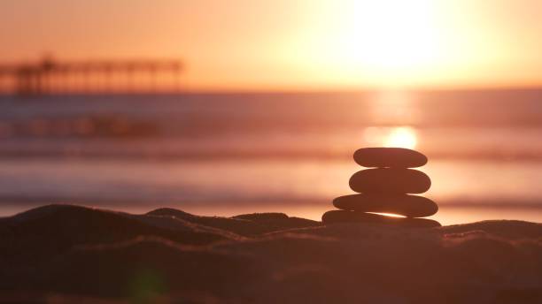 istock Stack of pebble stones, sandy ocean beach, sunset sky. Rock balancing by water. 1371920532