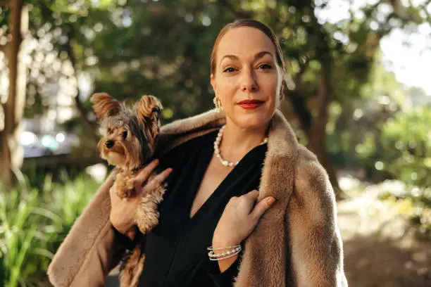 Photo of Elegant woman looking at the camera while holding her puppy