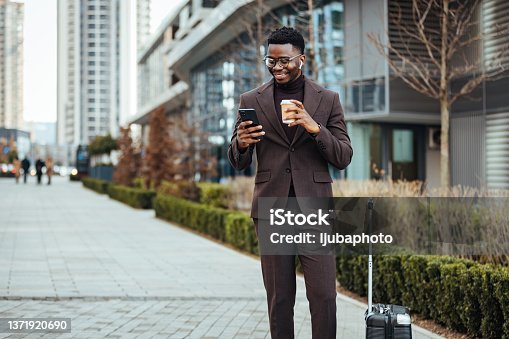 istock Smiling businessman with smart phone and cup 1371920690