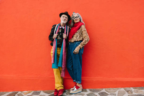 istock Mature couple standing together against a red wall 1371920737