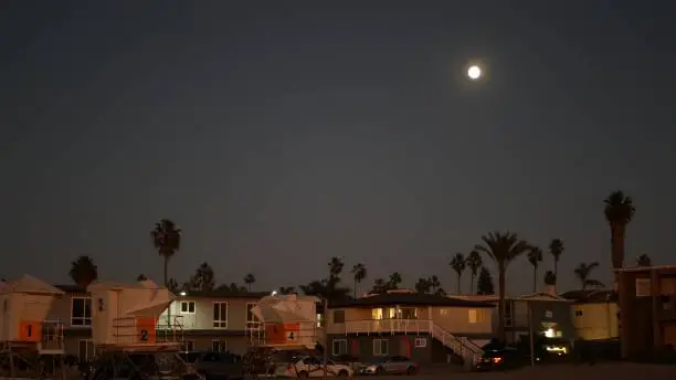 Photo of Palm trees and moon in twilight sky, California coast lifeguard, beach houses.