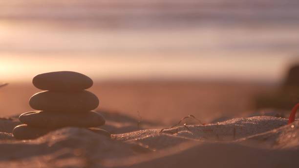 istock Stack of pebble stones, sandy ocean beach, sunset sky. Rock balancing by water. 1371922453