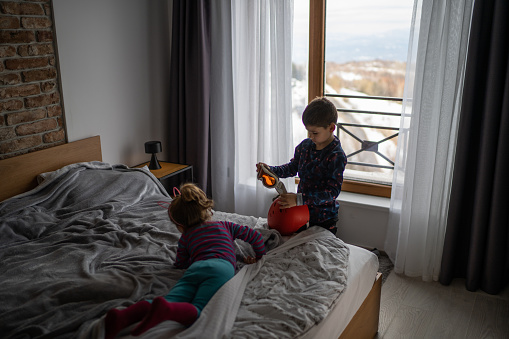 Brother and sister playing in bedroom, boy holding ski goggles