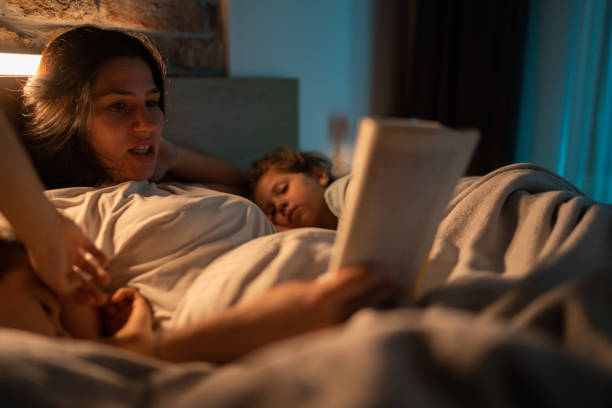 istock Mother reading stories to her kids before speeping while they lying in bed 1371925763