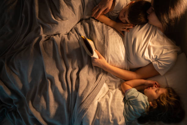 istock Mother reading stories to her kids before speeping while they lying in bed 1371925929