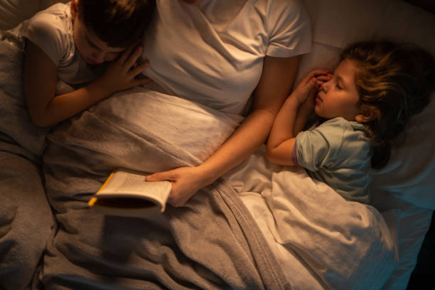 istock Mother reading stories to her kids before speeping while they lying in bed 1371926042