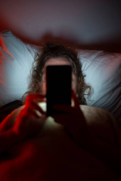 A lonely man in his early 40's on mobile in bed. stock photo