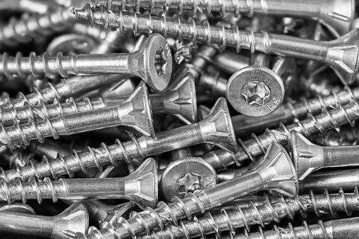 Closeup of metal fasteners heap in a tech background. Use to fasten wooden materials in civil engineering. Woodworking