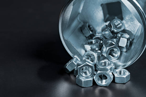 Small hex nuts spilled on heap in big socket for ratchet wrench with reflection on a black background Close-up of stainless steel hexagonal fasteners with threaded hole poured on pile in metal spanner. Bolting or screwing and maintenance works hex wrench stock pictures, royalty-free photos & images