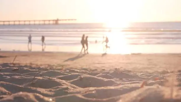 Photo of People walking on sandy Ocean Beach by pier at sunset, California coast, USA.