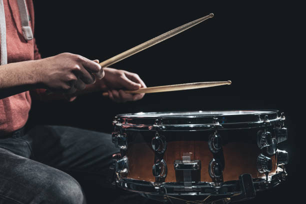 istock Snare drum and drummer's hands hitting drumsticks against a dark background. 1371927050