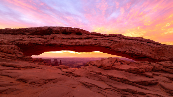 Mesa Arch (also known as Rotary Arch and Trail Arch) is a pothole arch on the eastern edge of the Island in the Sky mesa in Canyonlands National Park in northern San Juan County, Utah in the United States. Mesa Arch is a spectacular natural stone arch perched at the edge of a cliff with vast views of canyons, Monster Tower, Washer Woman Arch, Airport Tower, and the La Sal Mountains in the distance.