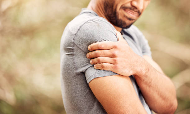 scatto di un uomo irriconoscibile che prova dolore alla spalla mentre si allena nella natura - shoulder pain physical injury human arm foto e immagini stock