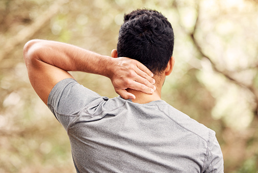 Rearview shot of an unrecognisable man experiencing neck pain while working out in nature