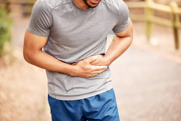 Shot of an unrecognisable man experiencing stomach ache while working out in nature Pain doesn't have to be the end of your fitness journey animal abdomen photos stock pictures, royalty-free photos & images