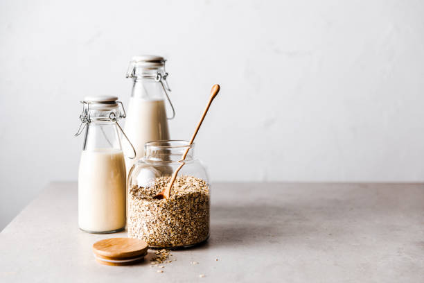 Oats in a glass jar with oat milk bottles on table