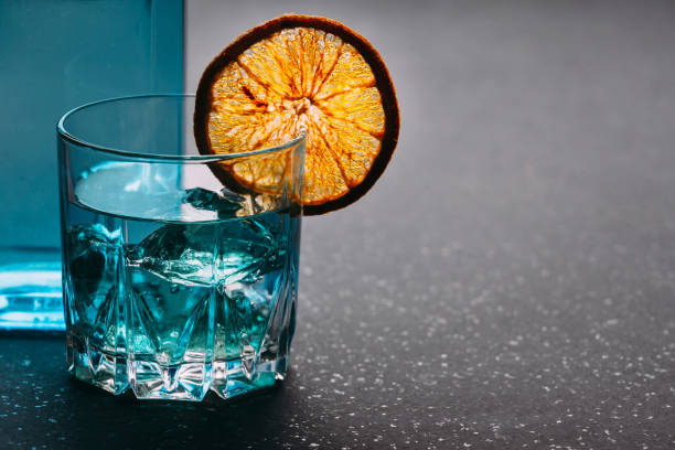 istock Gin in a glass with orange and ice on a black background. 1371933524
