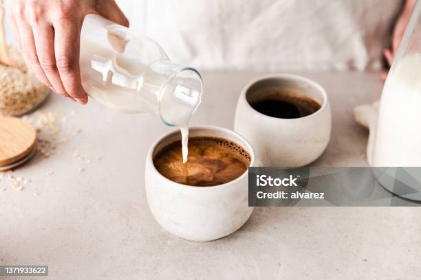 Closeup Of Pouring Oat Milk Into A Black Coffee C Stock Photo - Download Image Now - Coffee - Drink, Oat Milk, Coffee Cup