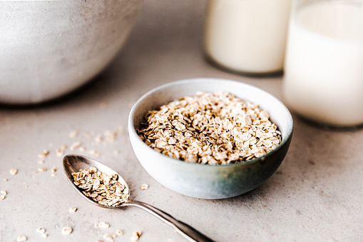 Close-up of oats in  bowl with spoon in table. Organic rolled oats in a ceramic bowl.