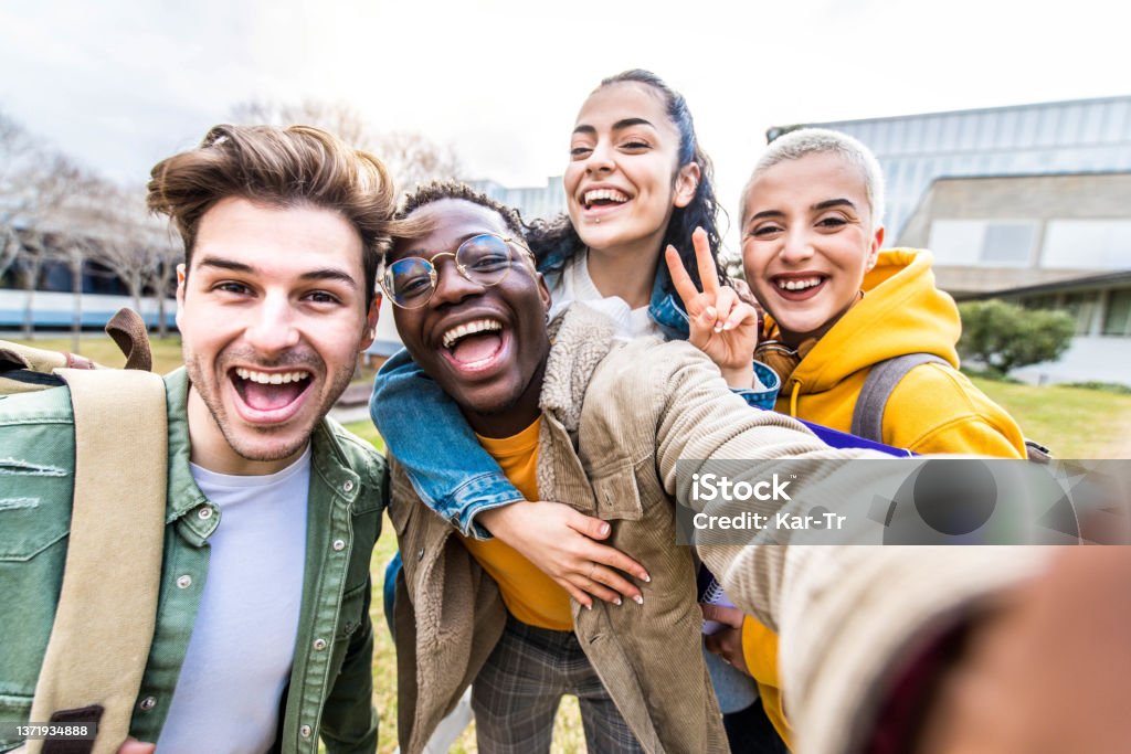 Multiracial students company taking selfie portrait in university campus - Multi ethnic best friends laughing at camera outside - Teens having fun together - Youth culture and school concept Student Stock Photo