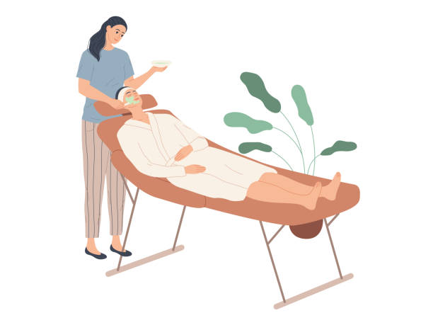 illustrations, cliparts, dessins animés et icônes de cosmétologue appliquant un masque cosmétique sur le visage du client dans le salon de spa. - massage table