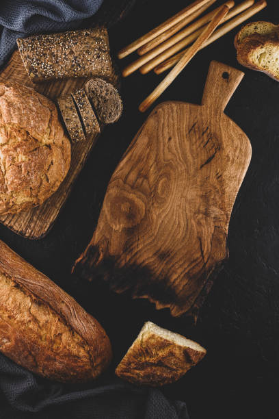 istock Freshly baked bread on a black table with artisan made  wodden cutting board 1371940023