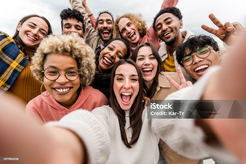 Multiracial friends taking big group selfie shot smiling at camera - Laughing young people standing outdoor and having fun - Cheerful students portrait outside school - Human resources concept Celebration Stock Photo