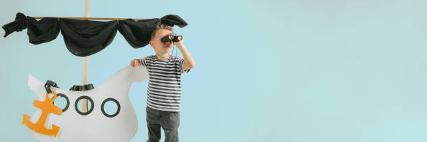 istock Little child boy playing with cardboard ship on blue wall background 1371941461