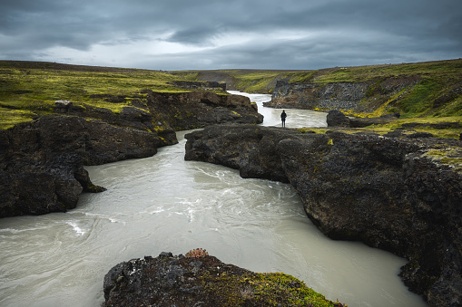 Woman standing by the glacial river in the Central Highlands of Iceland.