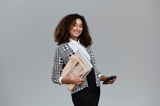 Office woman. Business woman with mobile phone, newspaper and laptop. Studio portrait