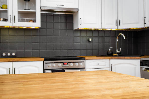 istock Selective focus on wood kitchen table island, blurred white home kitchen cabinets on background. Home products advertisement background concept. 1371946080