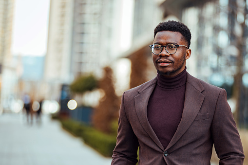 Young black cheerful man outdoors posing next to office center