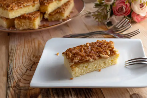 Delicious homemade baked butter cake with caramelized almonds. Slice of cake served on a plate on wooden table. Ready to eat