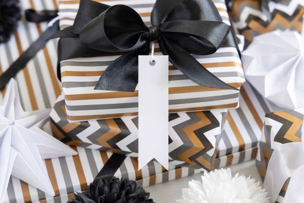 istock Wrapped present with blank vertical gift tag and black bow close up, label Mockup 1371951033
