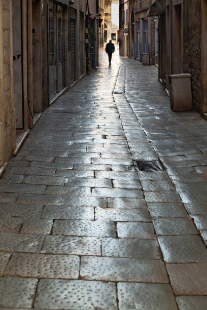 istock Man walking silhouette down narrow street 1371952823