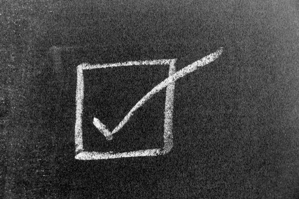 White color chalk hand drawing in right checkmark in square box shape on black board background