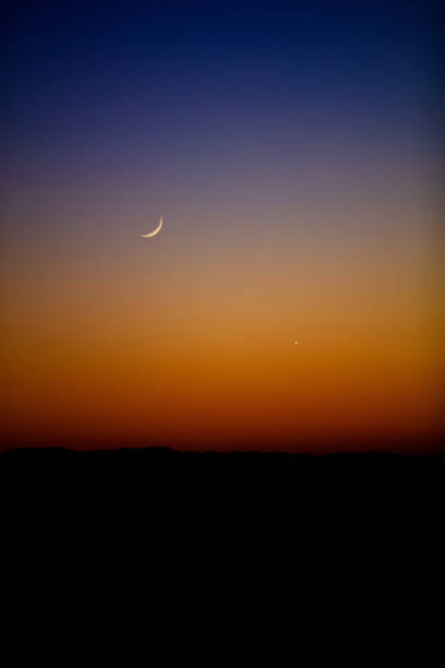 Crescent Moon, stars and planets on evening sky.