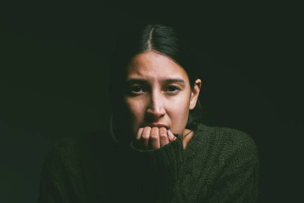 Shot of a young woman looking nervous against a dark background What is fear stopping you from doing? schizophrenia stock pictures, royalty-free photos & images