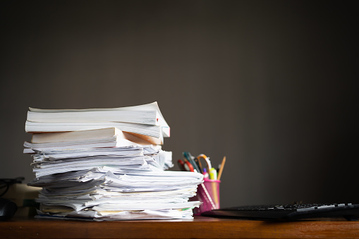 Businesswoman hands working in Stacks of paper files for searching and checking unfinished document achieves on folders papers at busy work desk office.