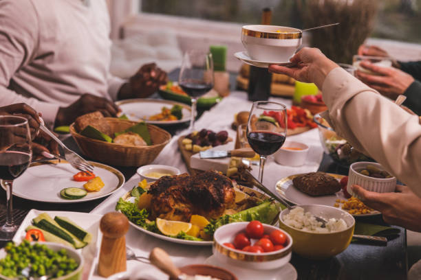 Cut out shot of various side dishes, roast chicken, red wine and other, served on a dining table for a group of unrecognizable friends to enjoy during a dinner party.