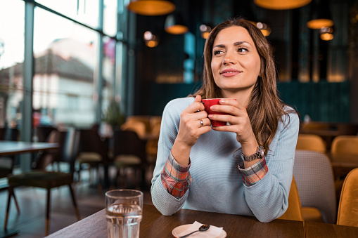 Beautiful young woman enjoying her morning coffee at her favorite cafe.