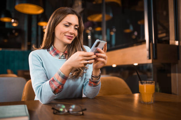 istock Cute young woman using phone at coffee shop. 1371964688
