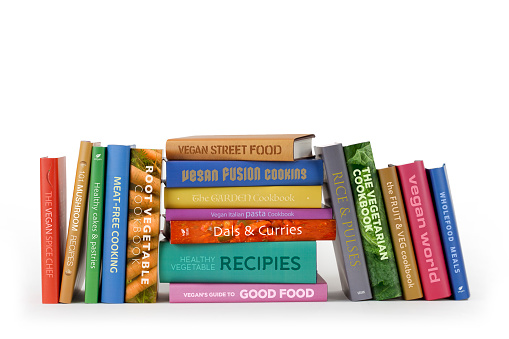 A row of vegan and vegetarian recipe books. Note: all books have been fabricated using original artwork and titles.
