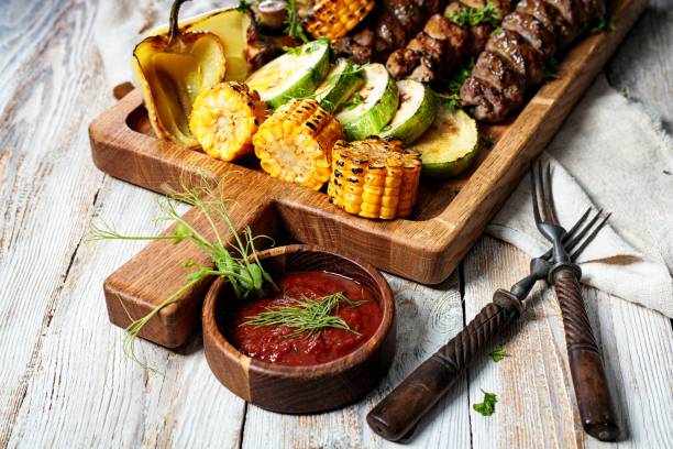 istock Assorted kebabs with grilled vegetables and herbs. Appetizing fried meat, corn, zucchini and mushrooms. Close-up 1371964699